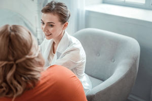 Woman sits in chair and talks to therapist in bulimia treatment program