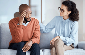 A man is sitting on a couch and participating in a psychotherapy program.